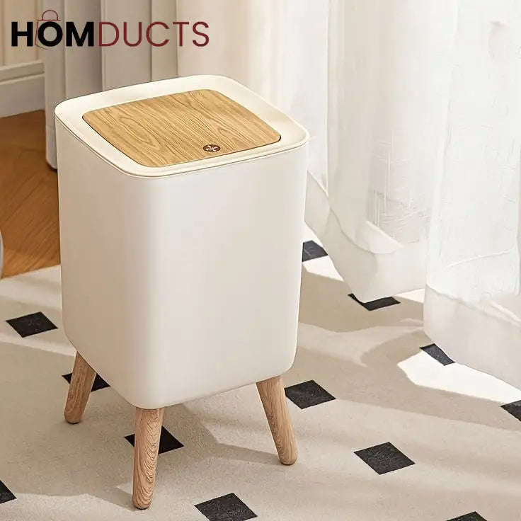 Square raised-leg trash bin with closed lid beside a curtain