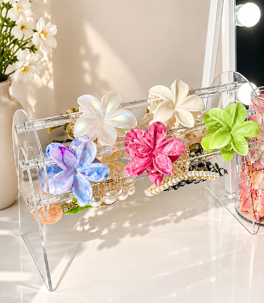 Clear acrylic hair clip stand displaying flower-shaped clips on a vanity