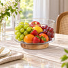 Clear glass serving bowl with wooden base in a bright dining setting