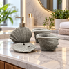 Grey seashell four-piece fibre bathroom accessory set on a vanity