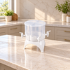 Four separate clear drink reservoirs with white taps in a rotating white cradle