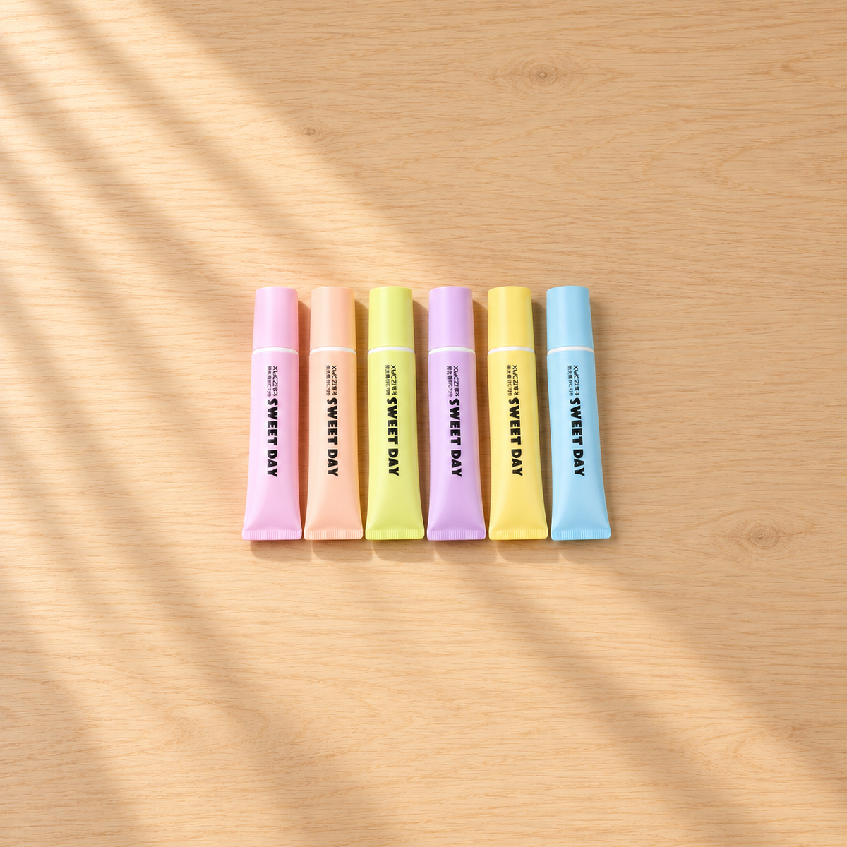 Six pastel tube-shaped SWEET DAY highlighters on a light wooden desk