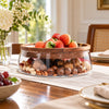 Clear glass serving bowl with thick wooden rim in a dining setting
